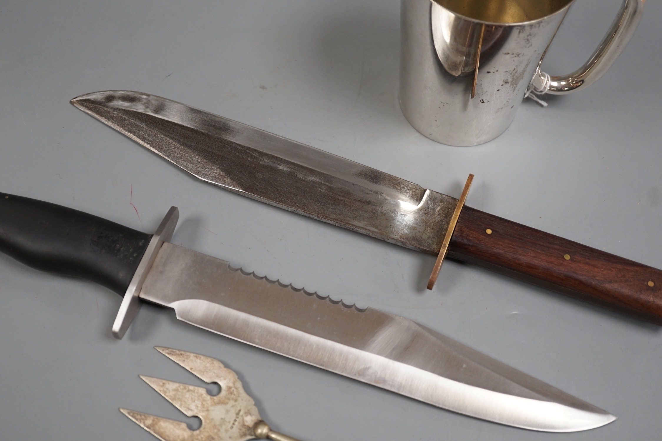 Two Bowie knives and a mug and a fork